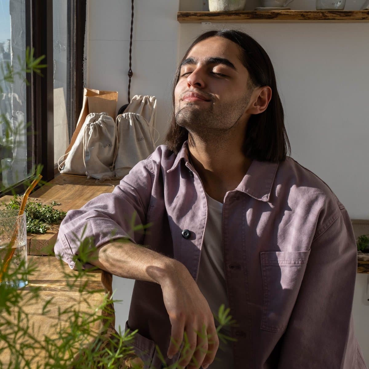 Un homme, les yeux fermés, profite du soleil près d'une fenêtre.